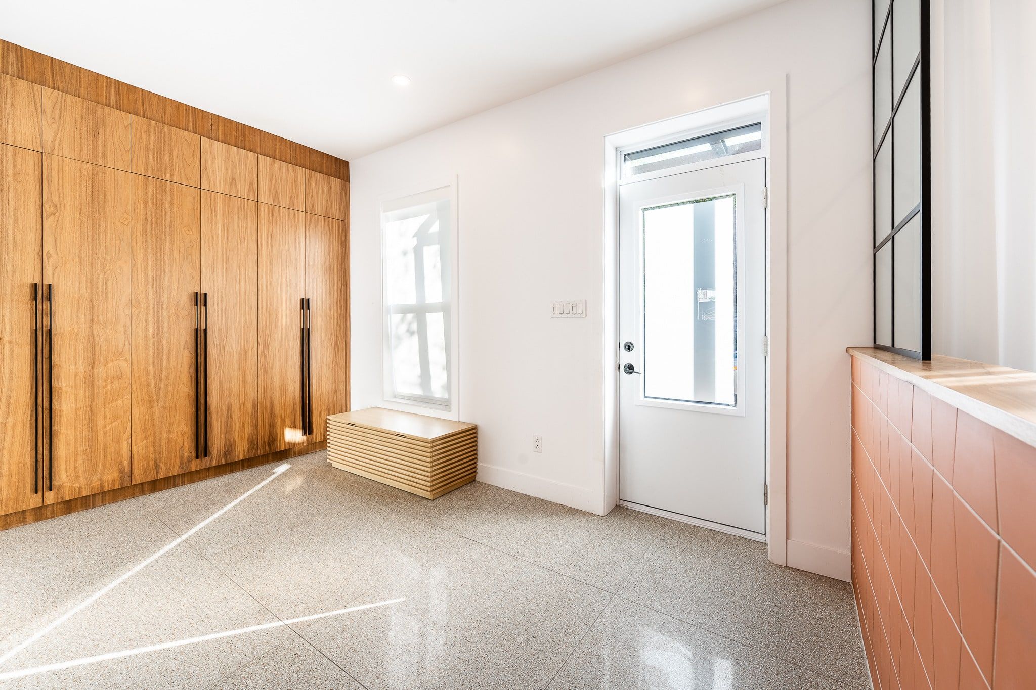 Hall d’entrée rénové à Rosemont : penderie pleine hauteur en noyer, plancher de terrazzo et banc en bois