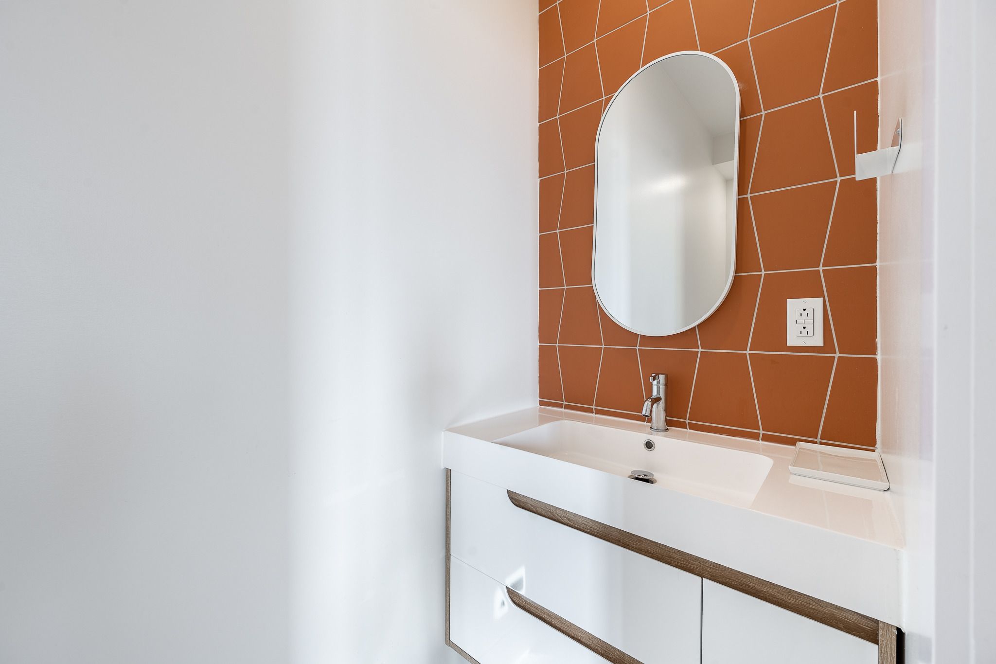 Petite salle de bain rénovée à Rosemont : céramique terracotta, miroir ovale et vanité blanche