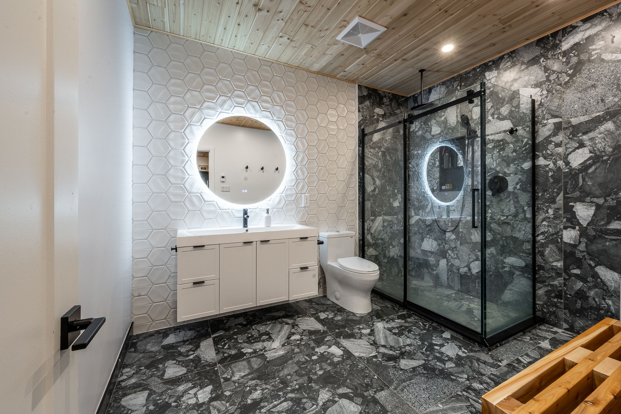 Salle de bain avec douche vitrée et miroir rond rétroéclairé